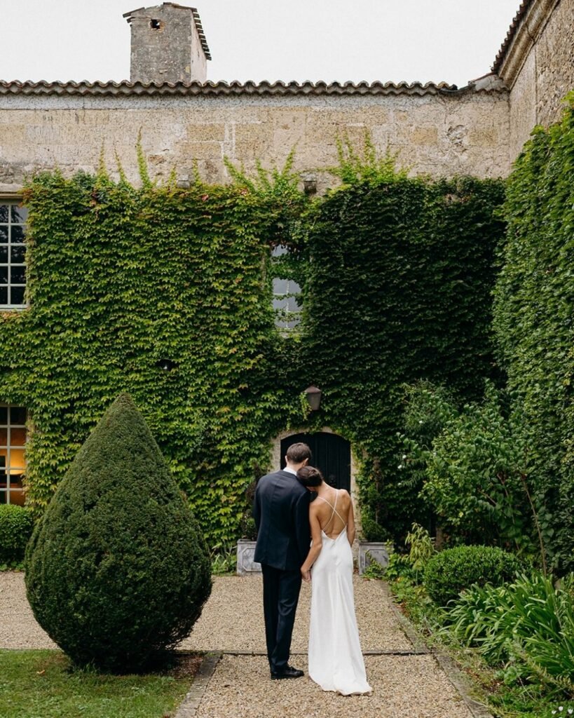 Bride and groom share a tender moment in the lush ivy-covered courtyard of Château Rigaud.