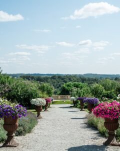 Scenic garden pathway lined with colorful flower arrangements, overlooking lush countryside at Domaine d'Essendiéras.