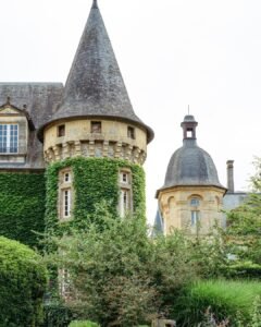 Ivy-covered medieval tower at Domaine d'Essendiéras, surrounded by lush greenery creating a fairytale atmosphere.