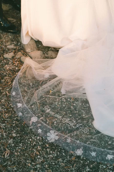 Close-up of the bride’s veil embroidered with “Forever and Always” beside the train of her gown at Liopetro.