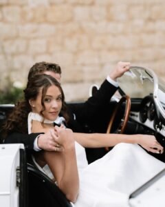 Bride and groom share an intimate moment seated in a classic car during their elegant wedding at Finca Morneta, captured by Sharon Cudworth