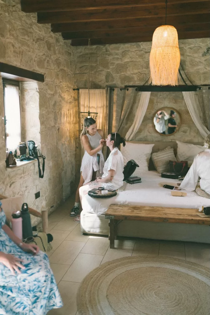 A candid moment during bridal makeup in a rustic stone-walled room at Liopetro.