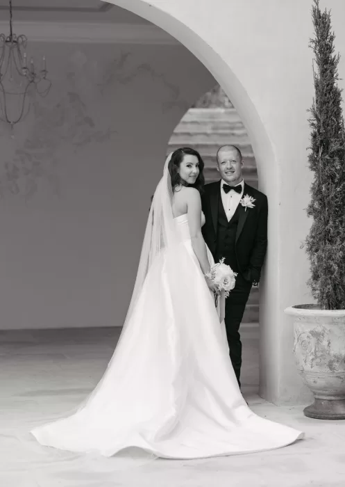 Black and white portrait of bride and groom framed by arch at Mas Torroella