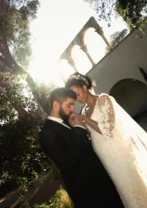 Tender moment between bride and groom beneath Mas Torroella’s sunlit arches.
