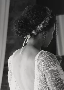 Bride with natural curls and a floral crown captured from behind, highlighting the lace dress and romantic styling at Mas Torroella.