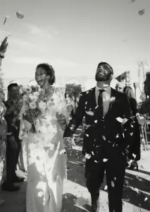 Just married couple laughing joyfully as flower petals fall during their confetti exit at Mas Torroella.