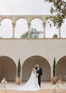 Couple standing beneath elegant arches in serene Mas Torroella courtyard