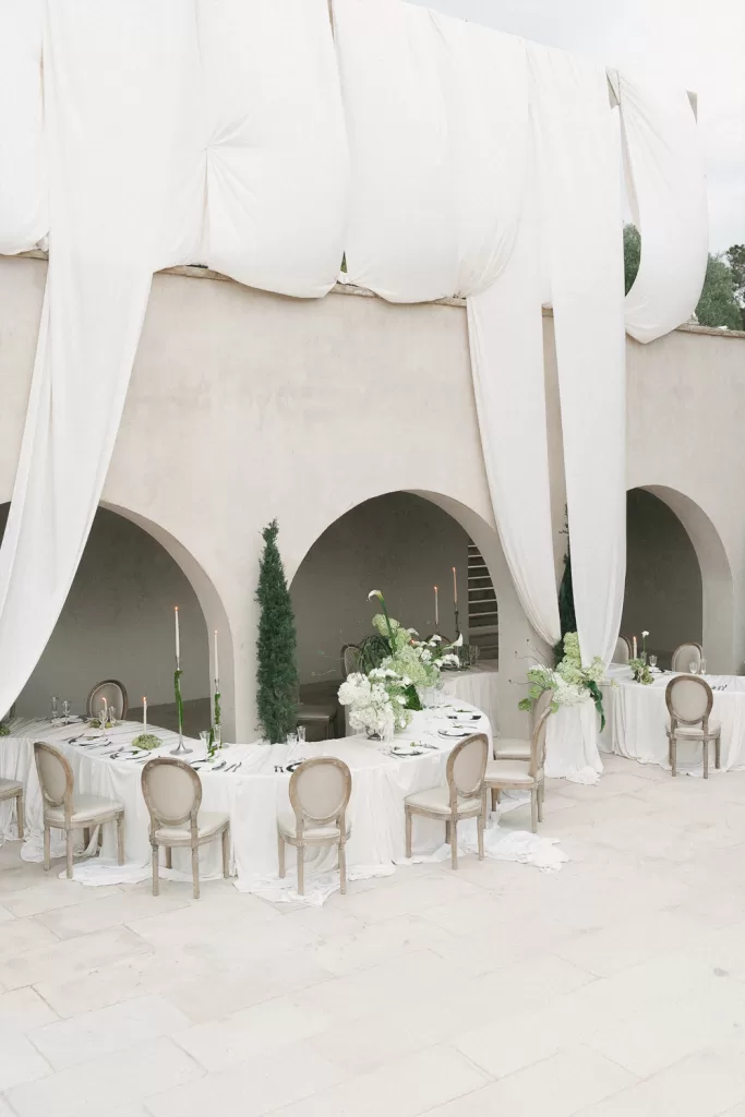 Softly draped arches frame chic reception tables in neutral tones at Mas Torroella.
