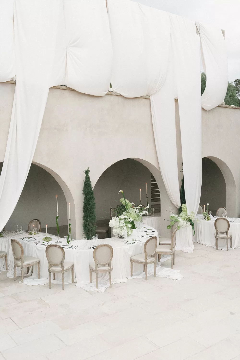 Softly draped arches frame chic reception tables in neutral tones at Mas Torroella.