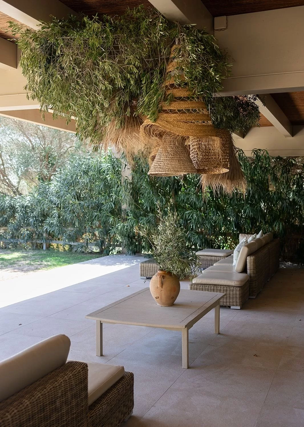 Covered lounge area at Mas Torroella with rattan furniture and overhead foliage