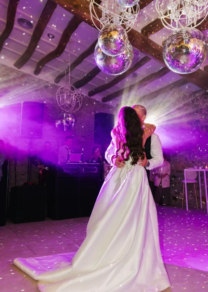 A romantic embrace on the dance floor at Mas Torroella, surrounded by purple lights and glittering disco balls.