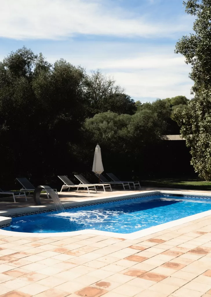 Peaceful outdoor pool surrounded by trees and loungers at Mas Torroella