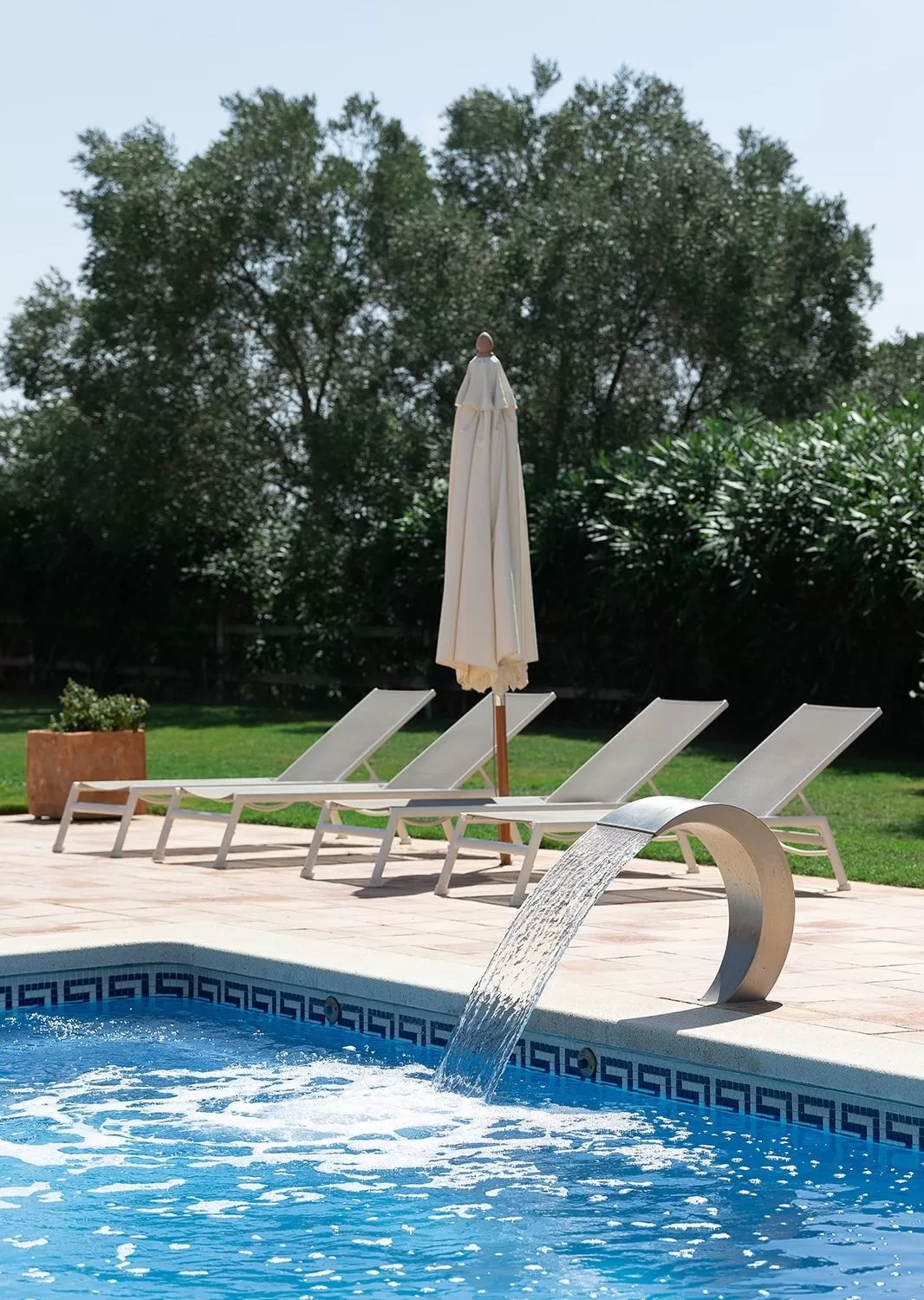 Poolside loungers and umbrella on a sunny afternoon at Mas Torroella.