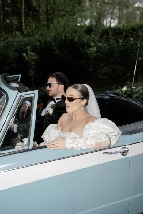 Bride and groom stylishly driving away in powder blue vintage convertible, photographed by Sharon Cudworth.