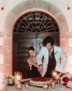 Newlyweds cutting a berry-topped wedding cake outside Villa Ivana’s grand arched doorway, surrounded by candlelight.