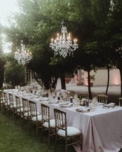 Crystal chandeliers glowing above a romantic outdoor reception table surrounded by trees at Villa Ivana.