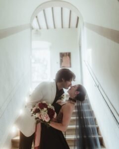 Groom dips bride for a romantic kiss on the staircase of Villa Ivana, with soft natural light illuminating the hallway.