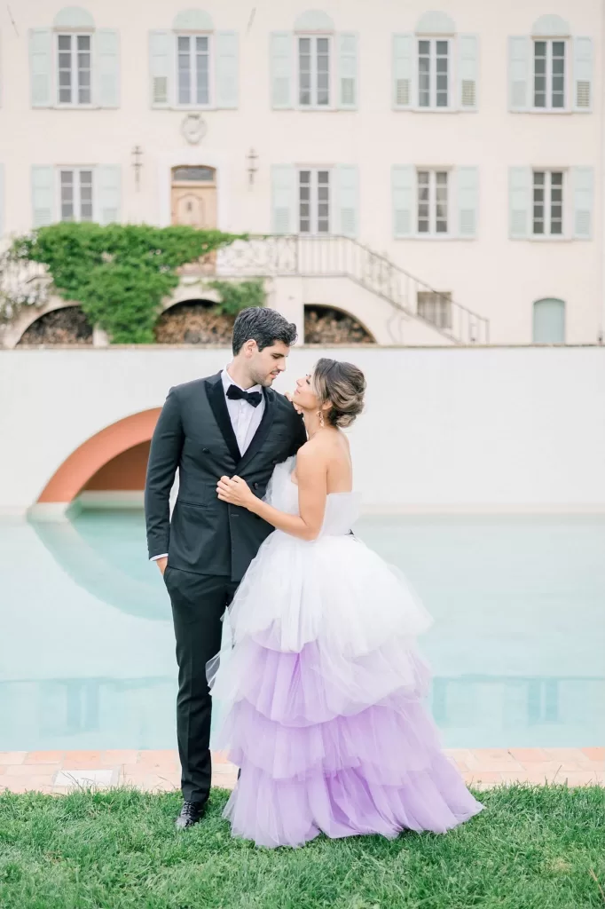 Intimate embrace of newlyweds beside the reflective pool at Bastide du Roy, with soft evening light highlighting their silhouette against the water.