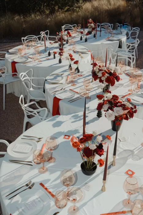 Aerial view of Ca Na Xica wedding tables with red and white flowers, gold cutlery, and rose-colored glassware.