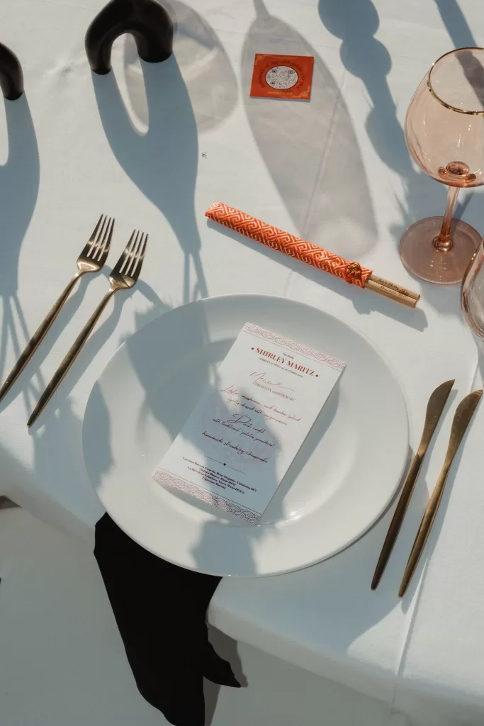 Wedding menu card on plate with chopsticks and gold cutlery at Ca Na Xica outdoor reception