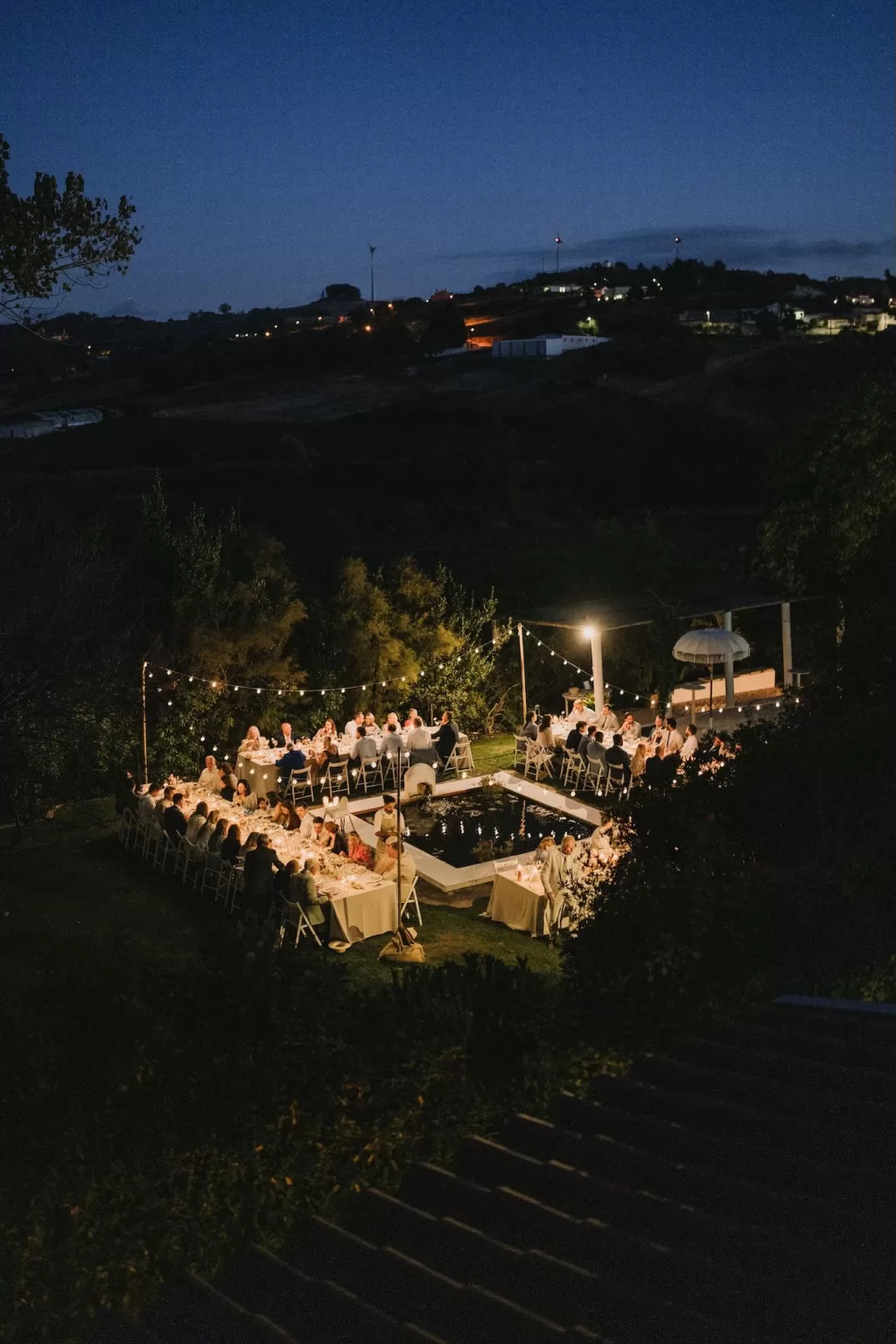 Nighttime view of the wedding reception at Casa Sacoto, with glowing string lights and guests dining outdoors.