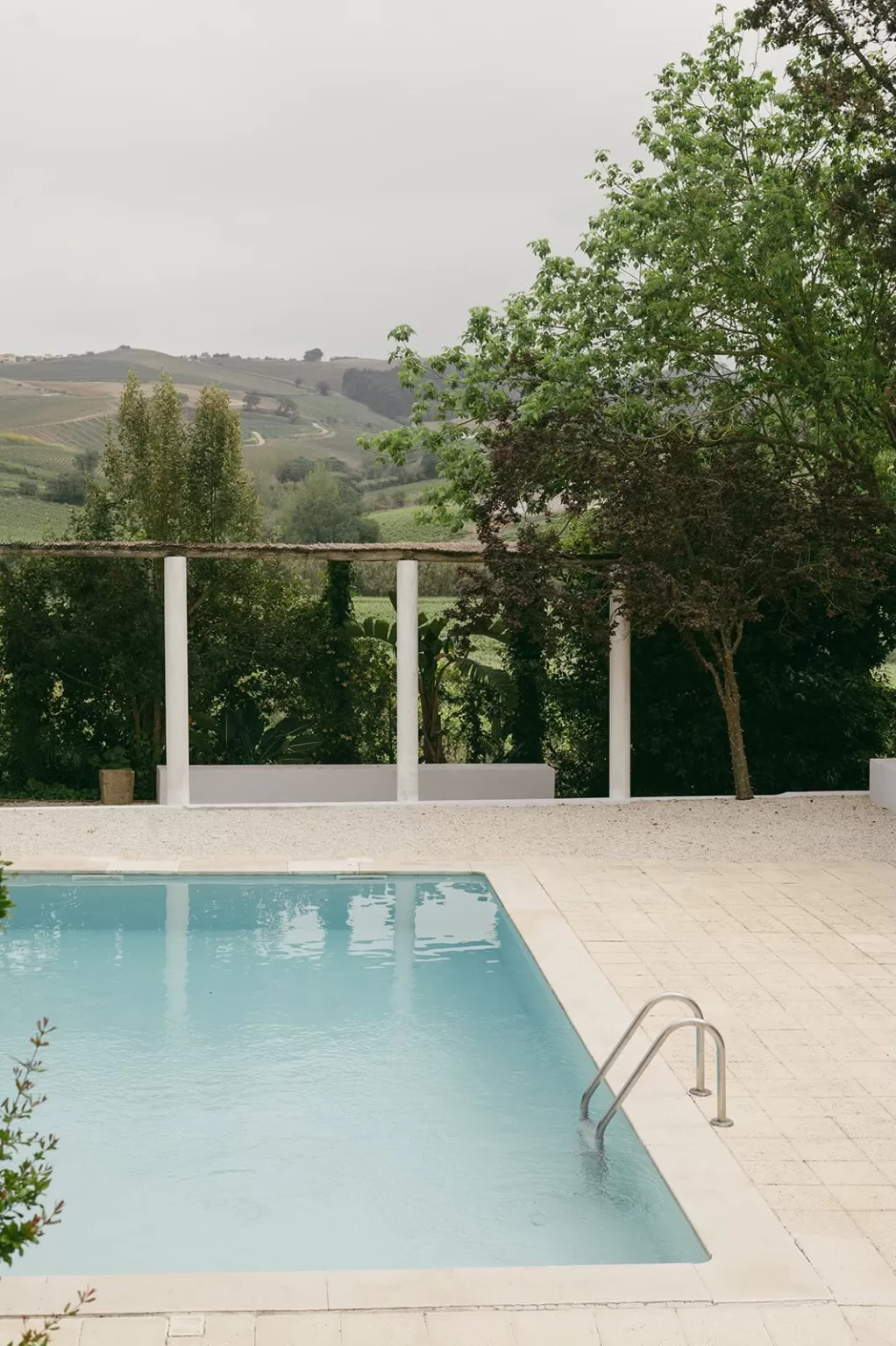 Serene poolside view at Casa Sacoto overlooking rolling hills under a soft summer sky.