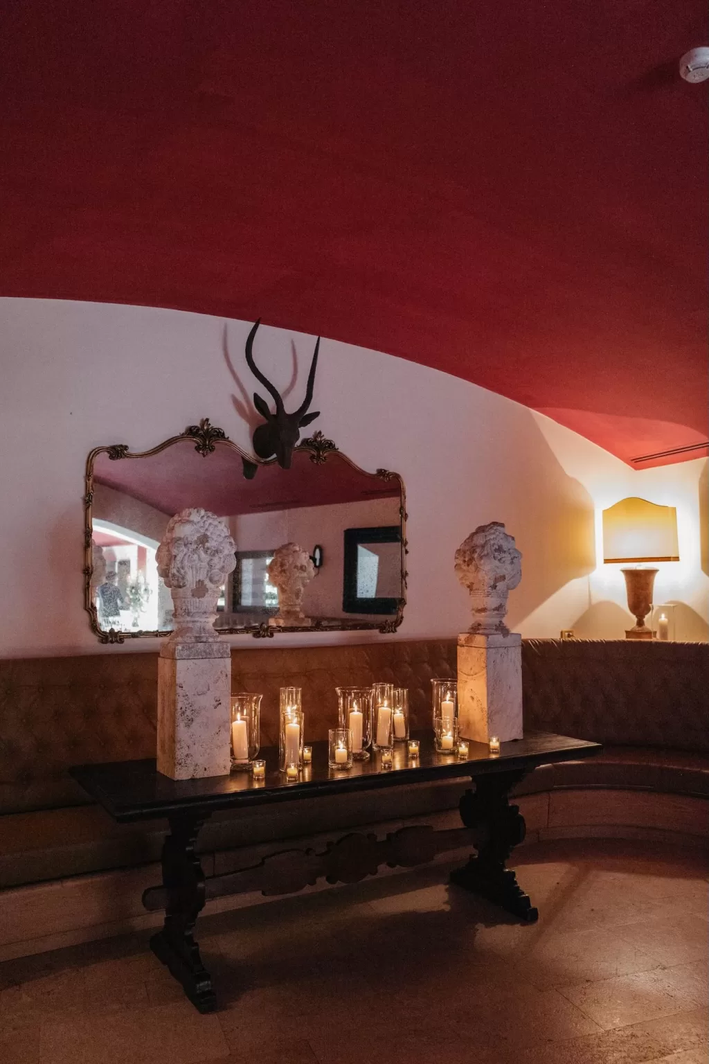 Candlelit table with stone busts and antique mirror inside Castello di Velona.
