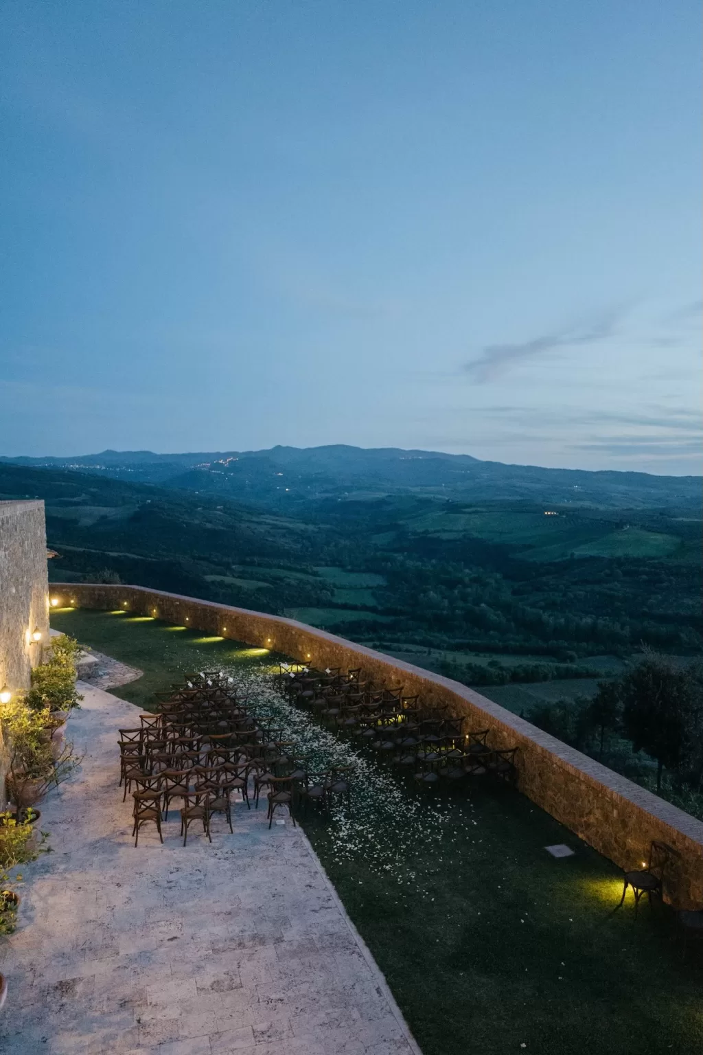 Evening wedding ceremony setup at Castello di Velona with chairs arranged under twilight skies.