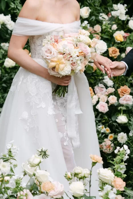 Close-up of the bride’s hands holding a white floral bouquet, with delicate embroidery on her gown at Euridge Manor.