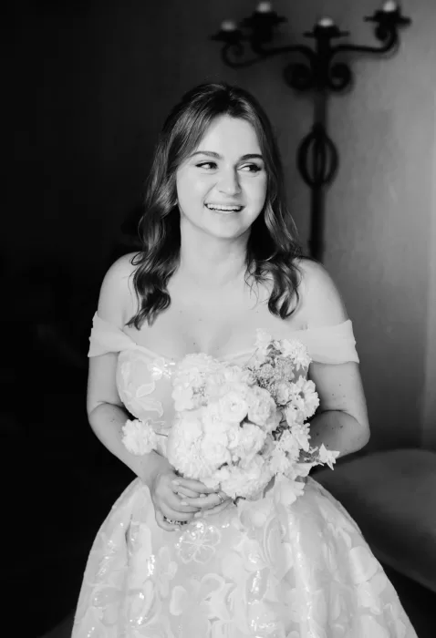 The bride smiles joyfully while holding her bouquet at Euridge Manor, her embroidered gown catching the light.