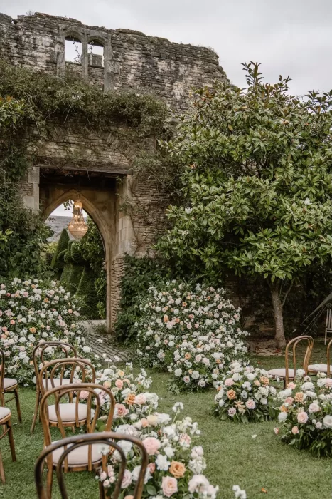 Romantic garden ceremony setup framed by flower meadows and ancient stone ruins at Euridge Manor.