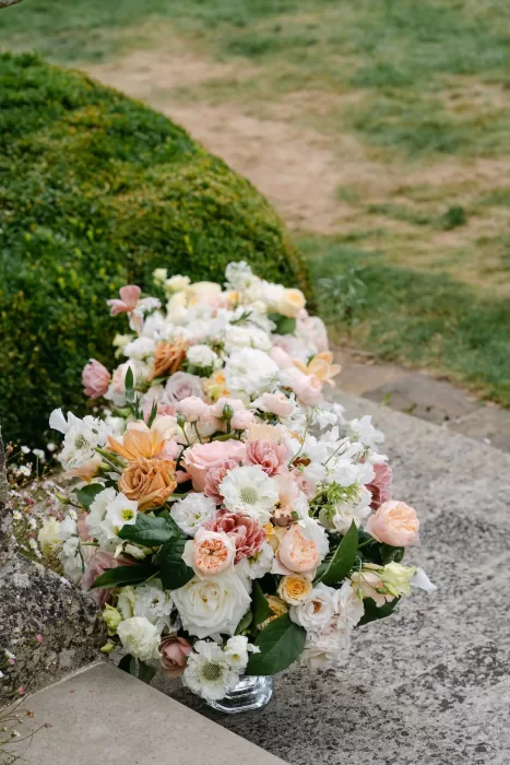 Lush pastel flower arrangement with roses and peonies placed on a stone step at Euridge Manor.