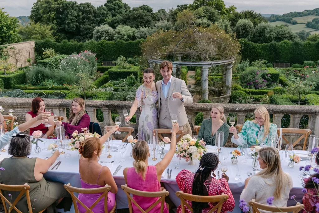Wedding couple toasting with guests on the terrace, overlooking Euridge Manor’s structured garden.