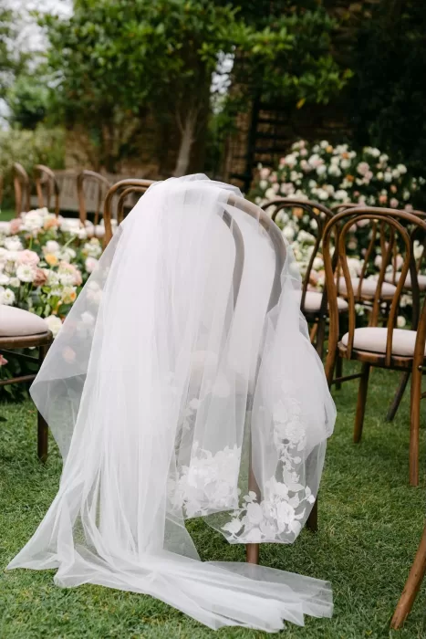 Bride’s embroidered veil draped over a ceremony chair in the lush gardens of Euridge Manor.