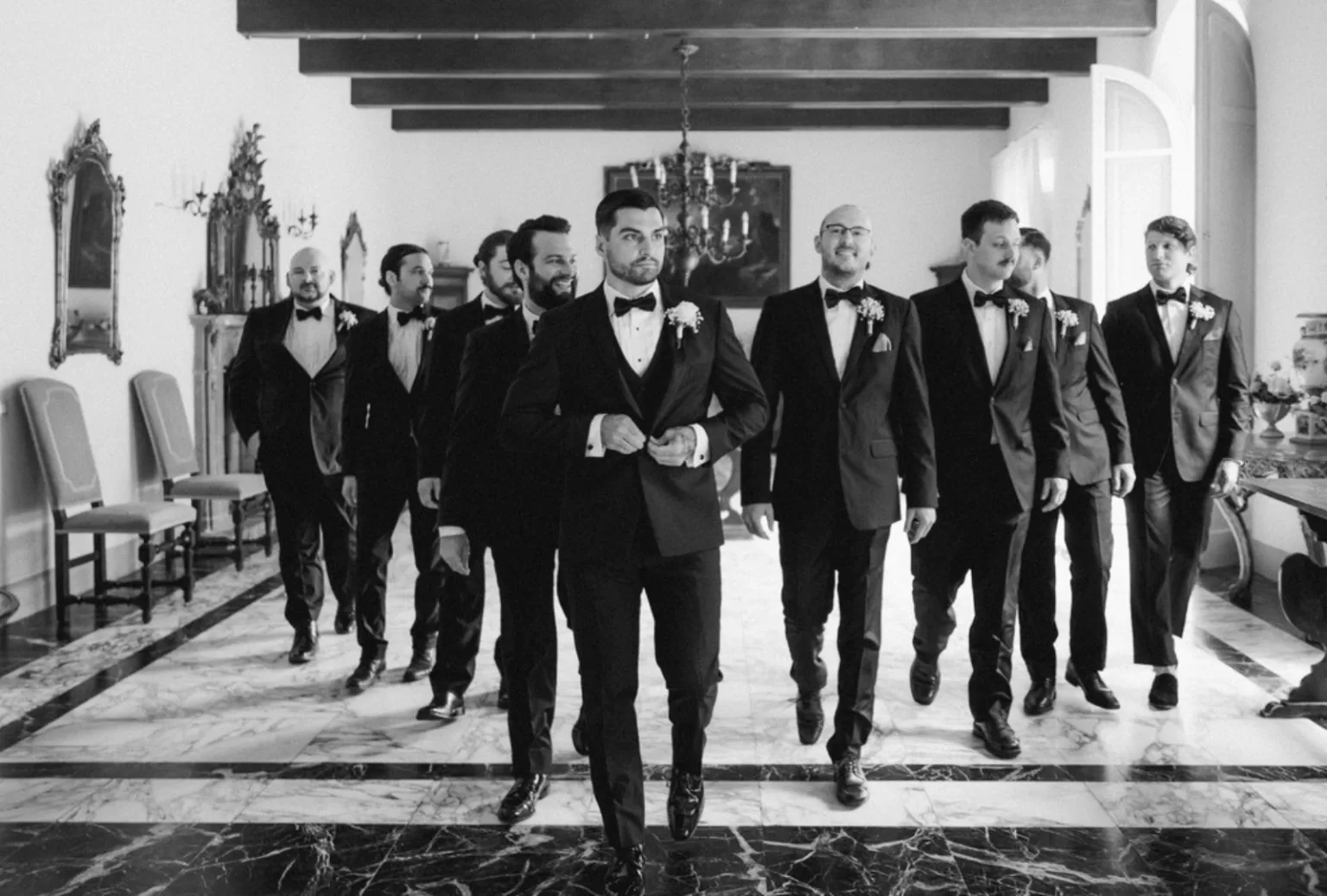 Groom and groomsmen in tailored suits standing in front of Villa Ravano’s grand entrance
