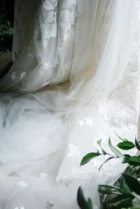 Close-up of a delicate lace bridal train with soft tulle and floral appliqué detailing.