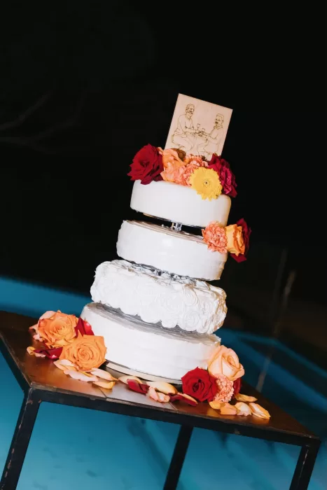 Wedding cake surrounded by rose petals, displayed by the poolside at Masia Casa del Mar.