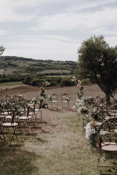 Outdoor wedding ceremony at Podere Calvaiola with floral arches and Tuscan hill views.