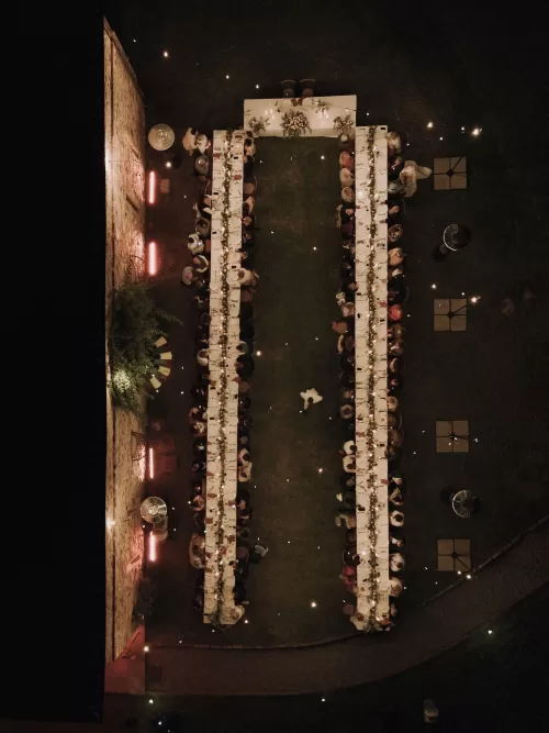 Overhead view of the U-shaped dinner setup at Podere Calvaiola, glowing with candles under the night sky.