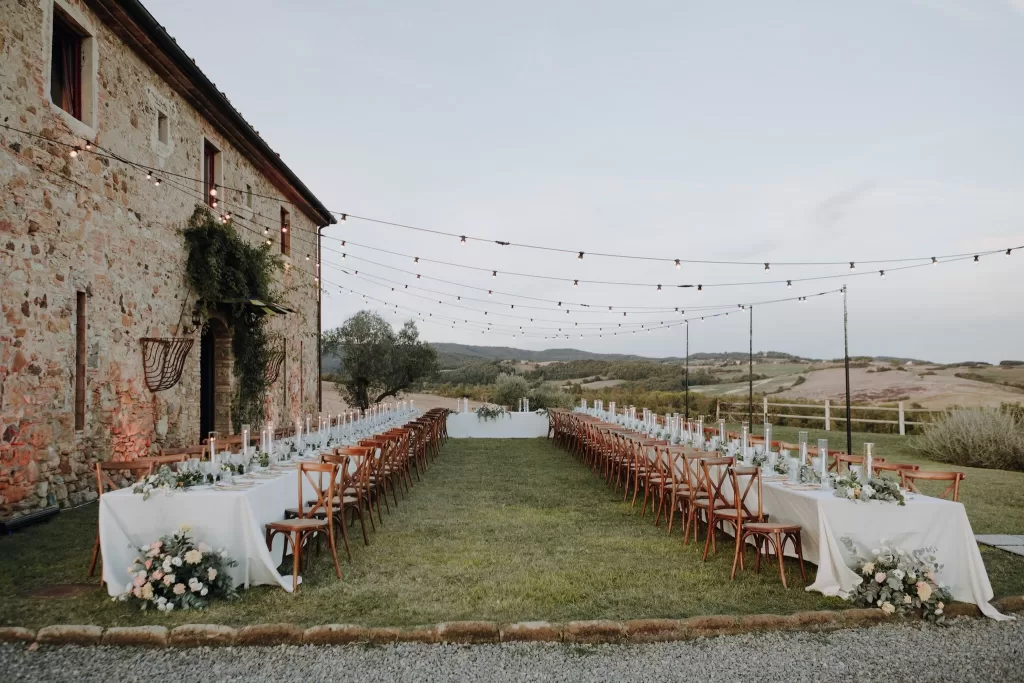 Long banquet tables under string lights at Podere Calvaiola, ready for an al fresco wedding celebration.