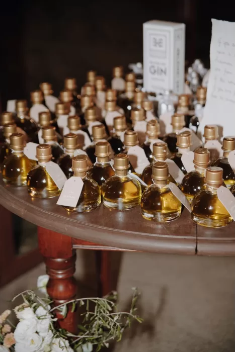 Personalized olive oil wedding favours in glass bottles displayed on a wooden table at Podere Calvaiola.