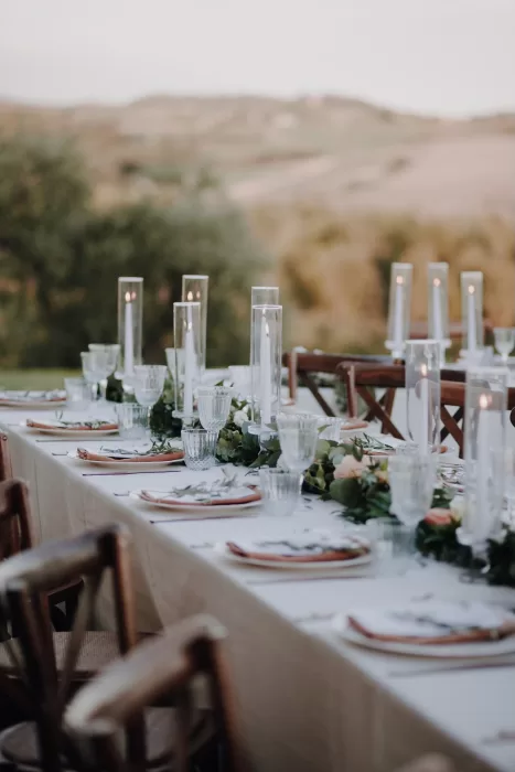 Romantic reception table at Podere Calvaiola with tall glass candles and soft floral details against rolling hills.