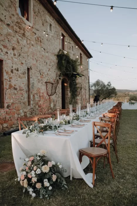 Elegant long table set for an outdoor wedding dinner at Podere Calvaiola, with soft florals and candlelight.
