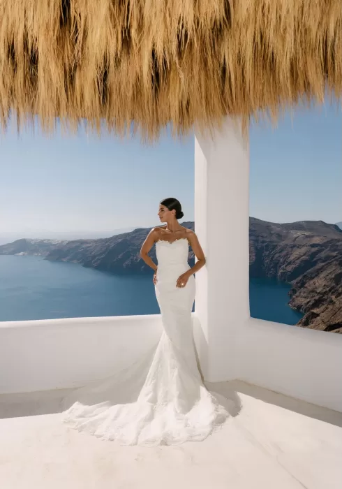 Bride poses atop a whitewashed rooftop hut, iconic of Rocabella Santorini’s Cycladic charm