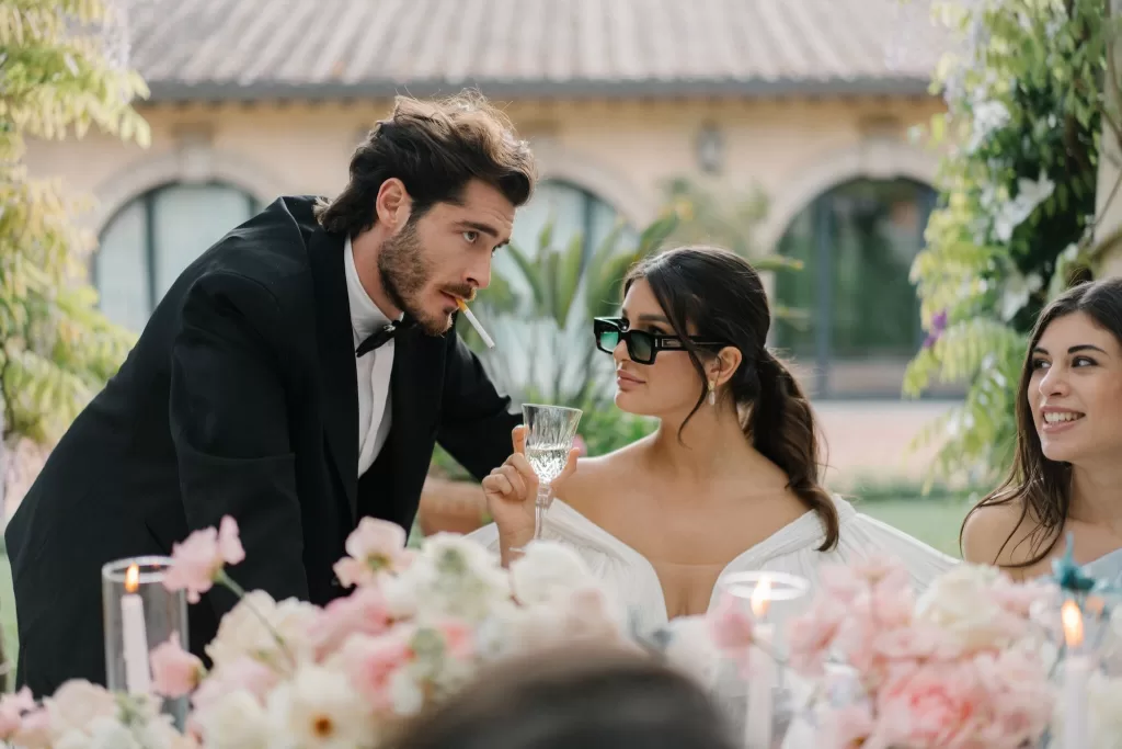 Stylish bride and groom enjoying a playful toast at Tenuta Corbinaia reception table.
