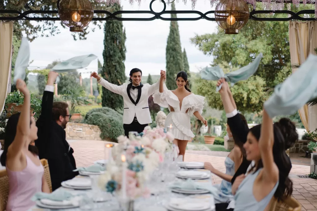 Newlyweds making a joyful entrance to their al fresco wedding dinner celebration at Tenuta Corbinaia.