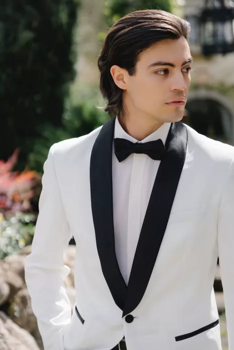 Close-up of the groom in a white tuxedo with black lapels at Tenuta Corbinaia, looking away thoughtfully.