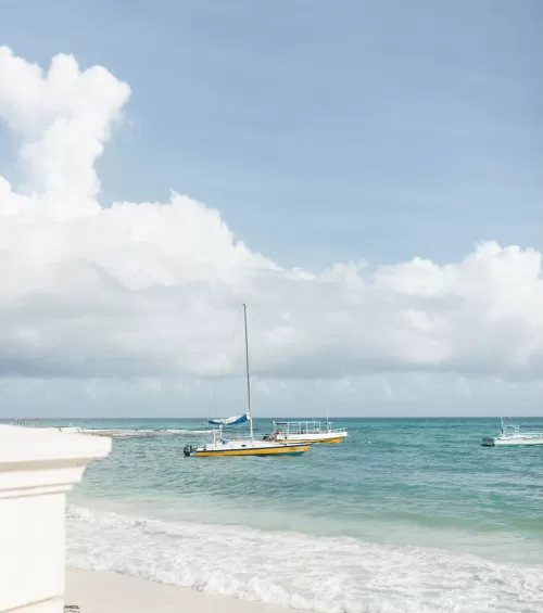 Yellow sailboat floating on turquoise waters near Villa La Joya’s private beach.