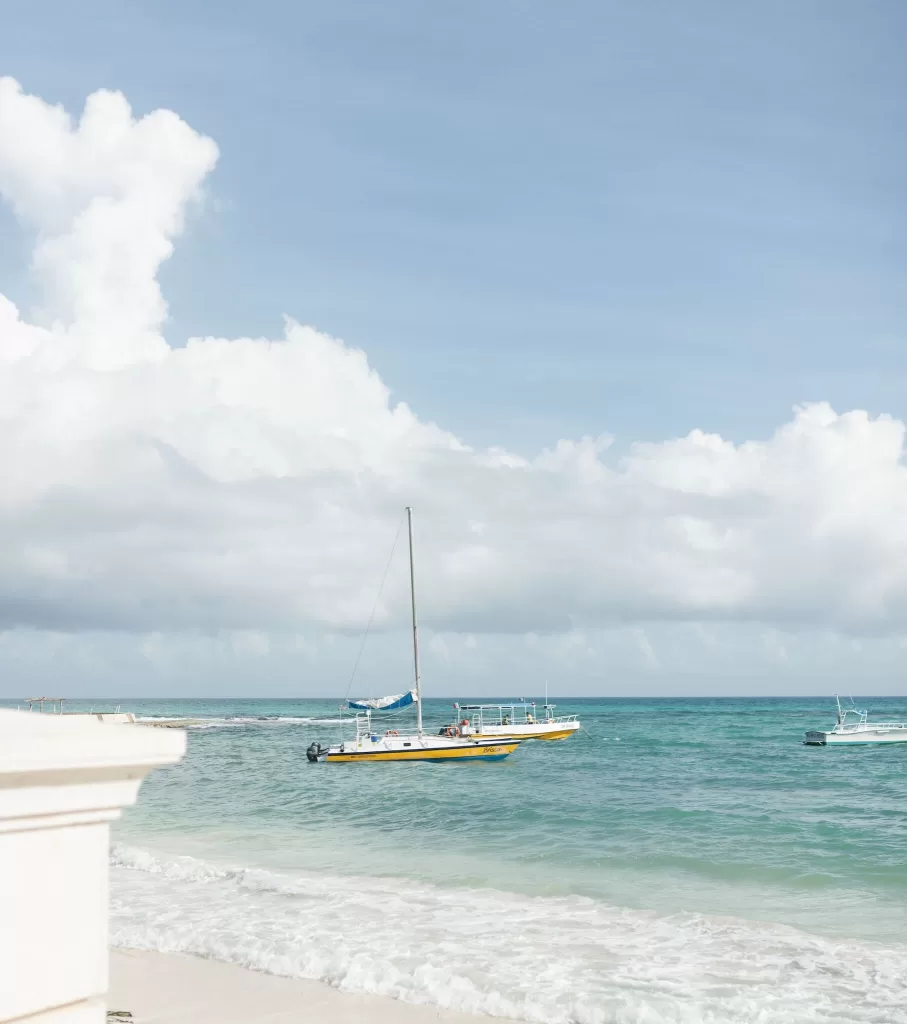 Yellow sailboat floating on turquoise waters near Villa La Joya’s private beach.