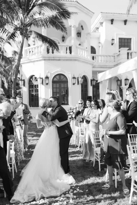 Newlyweds kiss at the end of their ceremony surrounded by cheering guests at Villa La Joya.
